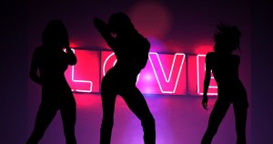womens bodies silhouette in front of pink neon love sign
